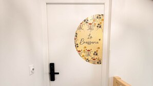 Uma porta branca com um adesivo circular escrito 'La Brasserie' e uma maçaneta preta.