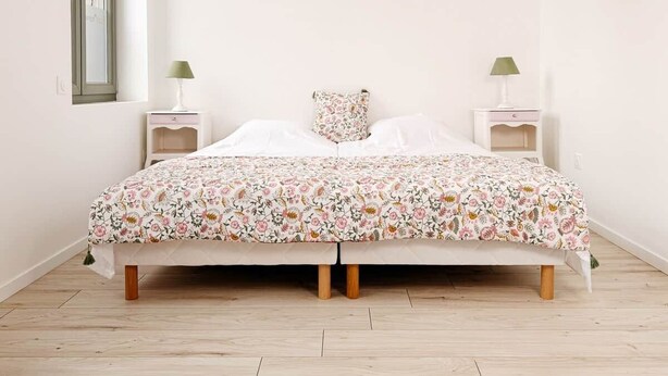 Un letto con copriletto floreale, due comodini con lampade e una finestra con vista.