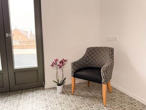 Una habitación con piso estampado, una silla de diseño geométrico y una orquídea en maceta.
