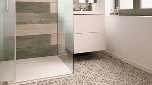 Un bagno moderno con cabina doccia in vetro, un mobile lavabo bianco e un'ampia finestra.