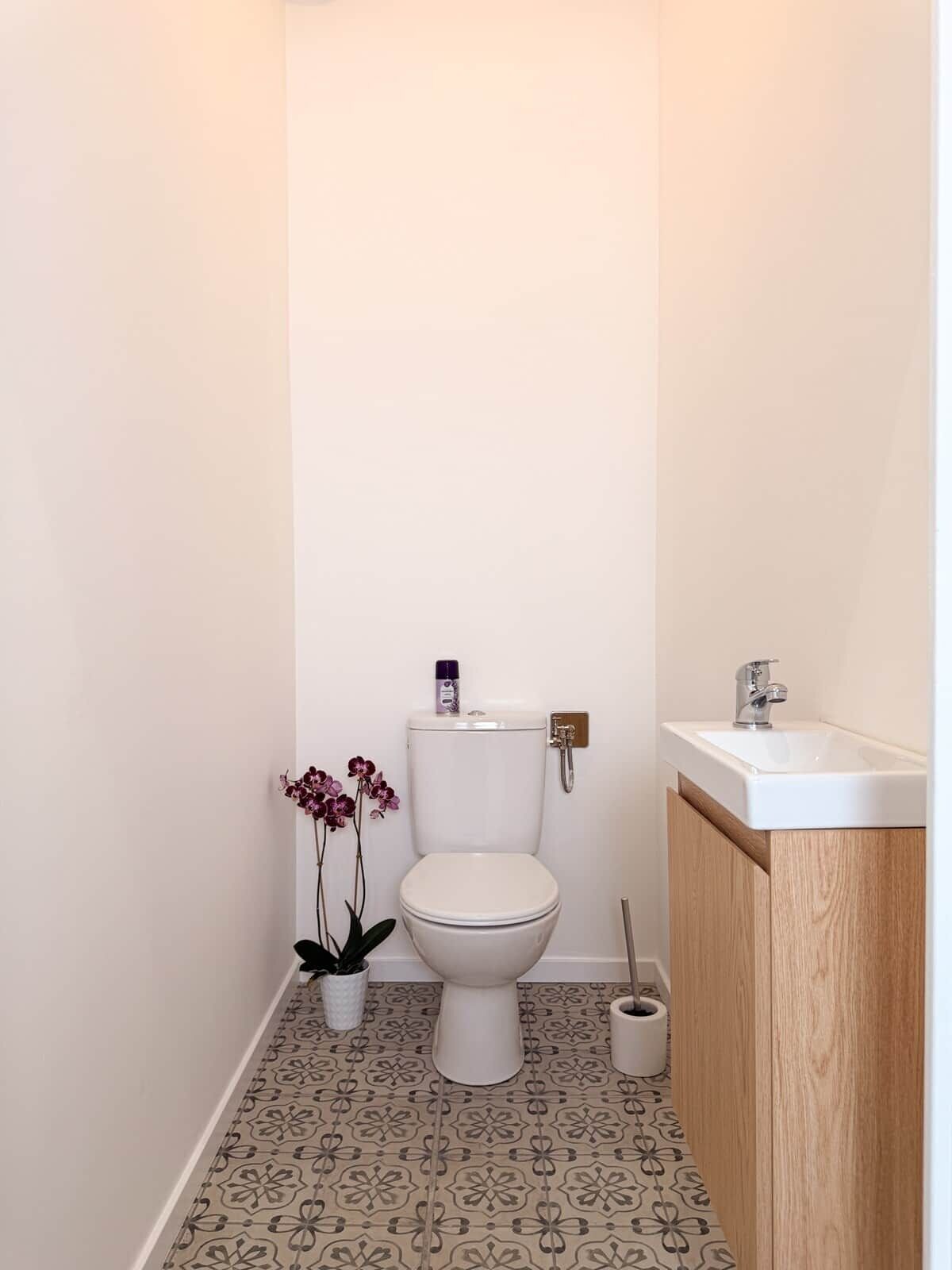 Une petite salle de bain avec des toilettes, un lavabo et une orchid ée en pot.