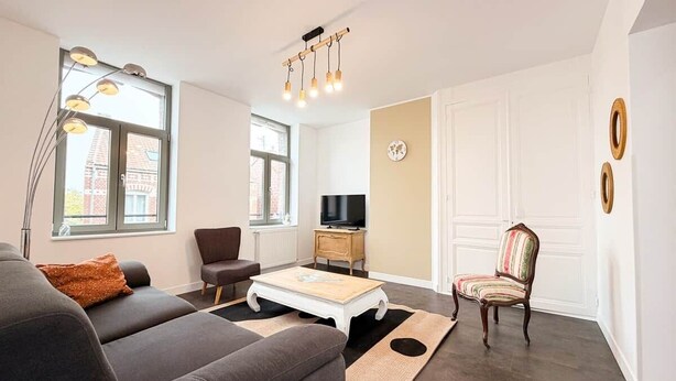 A living room with a sofa, armchair, TV stand, and a decorative chair.