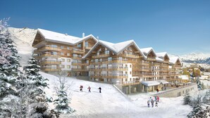 A multi-story hotel with a ski slope in the foreground, wooden exterior, and snow-covered mountains in the background.