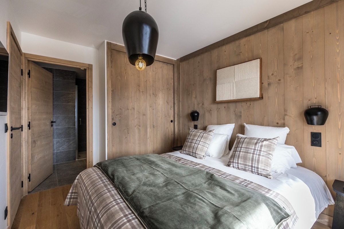 Un dormitorio con una cama, una lámpara colgante, una mesita de noche y una lámpara de pared.