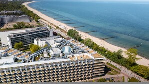 A coastal hotel with multiple floors, a beach view, and a long pier extending into the sea. - Marea Widok na Morze Studio Premium Hotel Seaside (gmina Parzęczew)