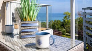 A balcony with a view of the sea, a potted plant, and two cups on a table. - Marea Widok na Morze Studio Premium Hotel Seaside (gmina Parzęczew)