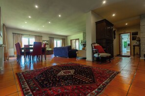 A spacious living area with a dining set, a sofa, and a patterned rug. - Quinta da Ponte - Family Refuge in Nature (Viseu)