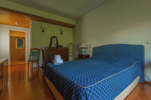Una camera da letto con un letto, una cassettiera, una lampada e una porta che dà su un'altra stanza.