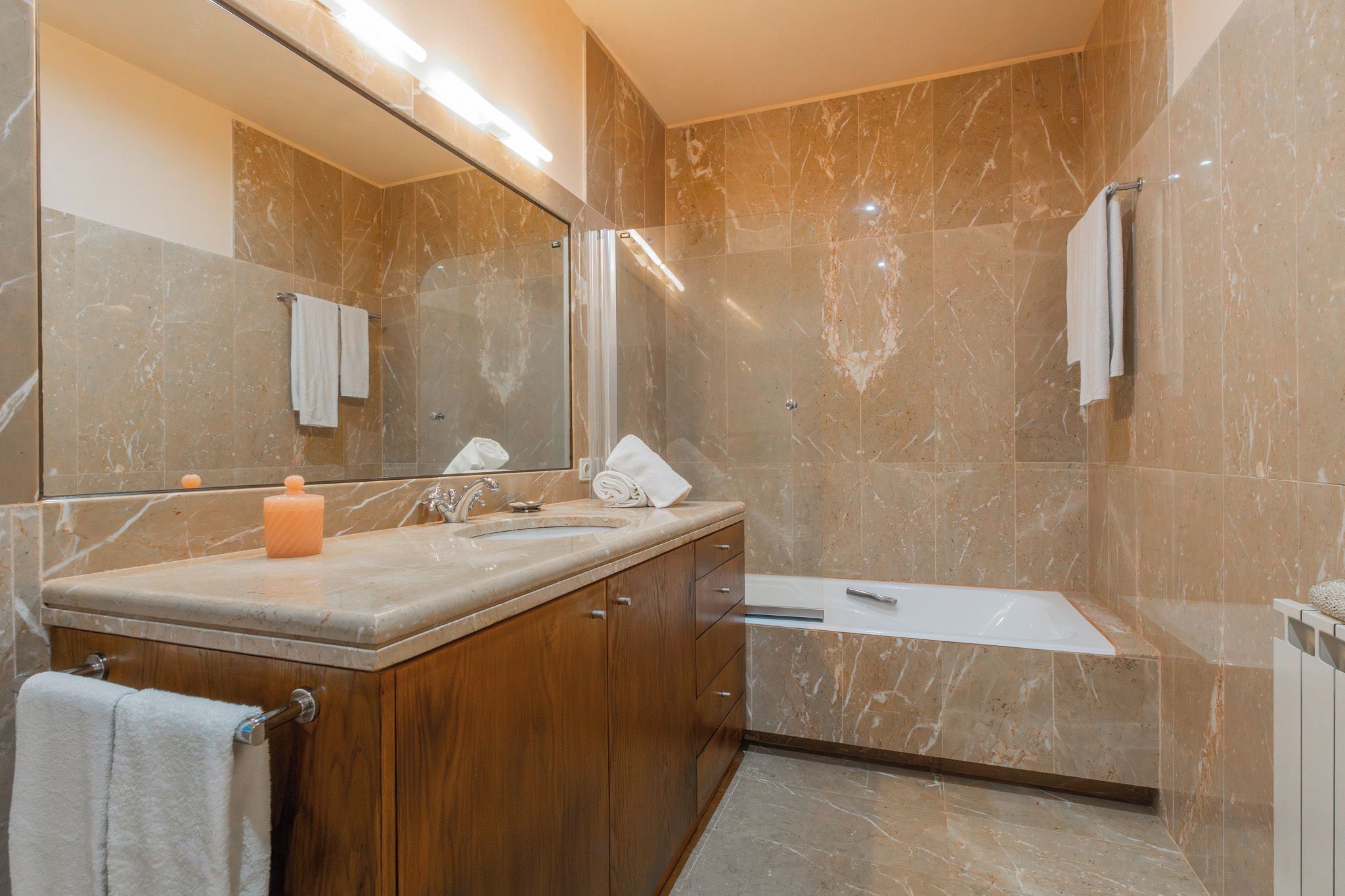 Ein modernes Badezimmer mit Waschtisch aus Marmor, einer Badewanne und einem großen Spiegel.