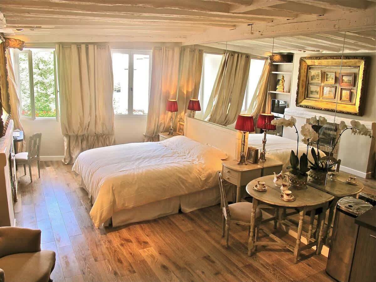 Ein Schlafzimmer mit Bett, Schreibtisch, Stuhl und Tisch mit Tassen und Untertellern.