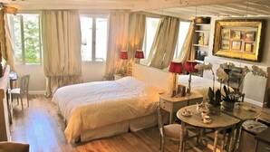 Ein Schlafzimmer mit Bett, Schreibtisch, Stuhl und Tisch mit Tassen und Untertellern.