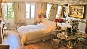Ein Schlafzimmer mit Bett, Schreibtisch, Stuhl und Tisch mit Tassen und Untertellern.