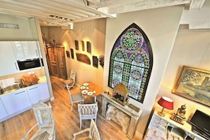 A dining area with a stained glass window, a fireplace, and a table set for four. - Charming Two Bedroom Suite - AC - At Notre-Dame (Paris)