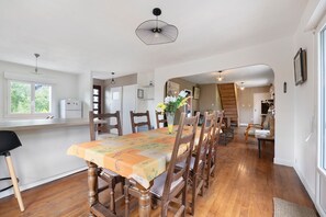 Un comedor con una larga mesa de madera, sillas, una araña y vistas a una escalera.