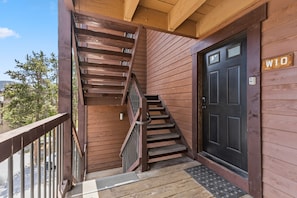 Ein Holzfassade mit einer schwarzen Tür, auf der 'W10' steht, einer Holztreppe und einem Metallgeländer.