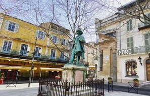Uma estátua em uma praça, com edifícios ao fundo.