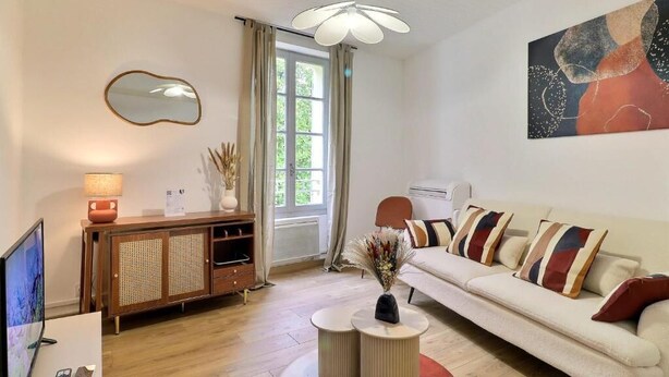 A living room with a sofa, a television, a cabinet, a mirror, and a painting on the wall. - Nuit étoilée (Arles)