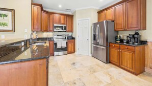 A kitchen with wooden cabinets, stainless steel appliances, and a granite countertop. - Sol and Sea Beach Compound w Pool and Boat House (Murrells Inlet)