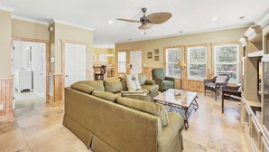 A spacious living room with a large sofa, a coffee table, and a ceiling fan. - Sol and Sea Beach Compound w Pool and Boat House (Murrells Inlet)