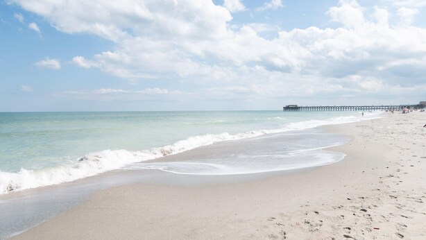 A beach with clear skies and a pier in the distance. - Sol and Sea Beach Compound w Pool and Boat House (Murrells Inlet)
