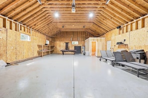 A spacious indoor area with a high ceiling, wooden beams, and a long bench along one wall.