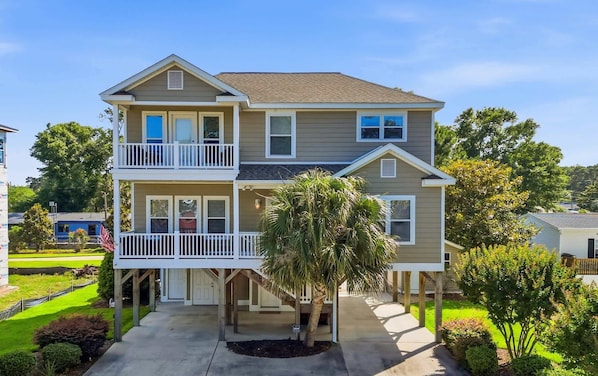 A two-story house with a balcony on the first floor, a front porch, and a driveway.