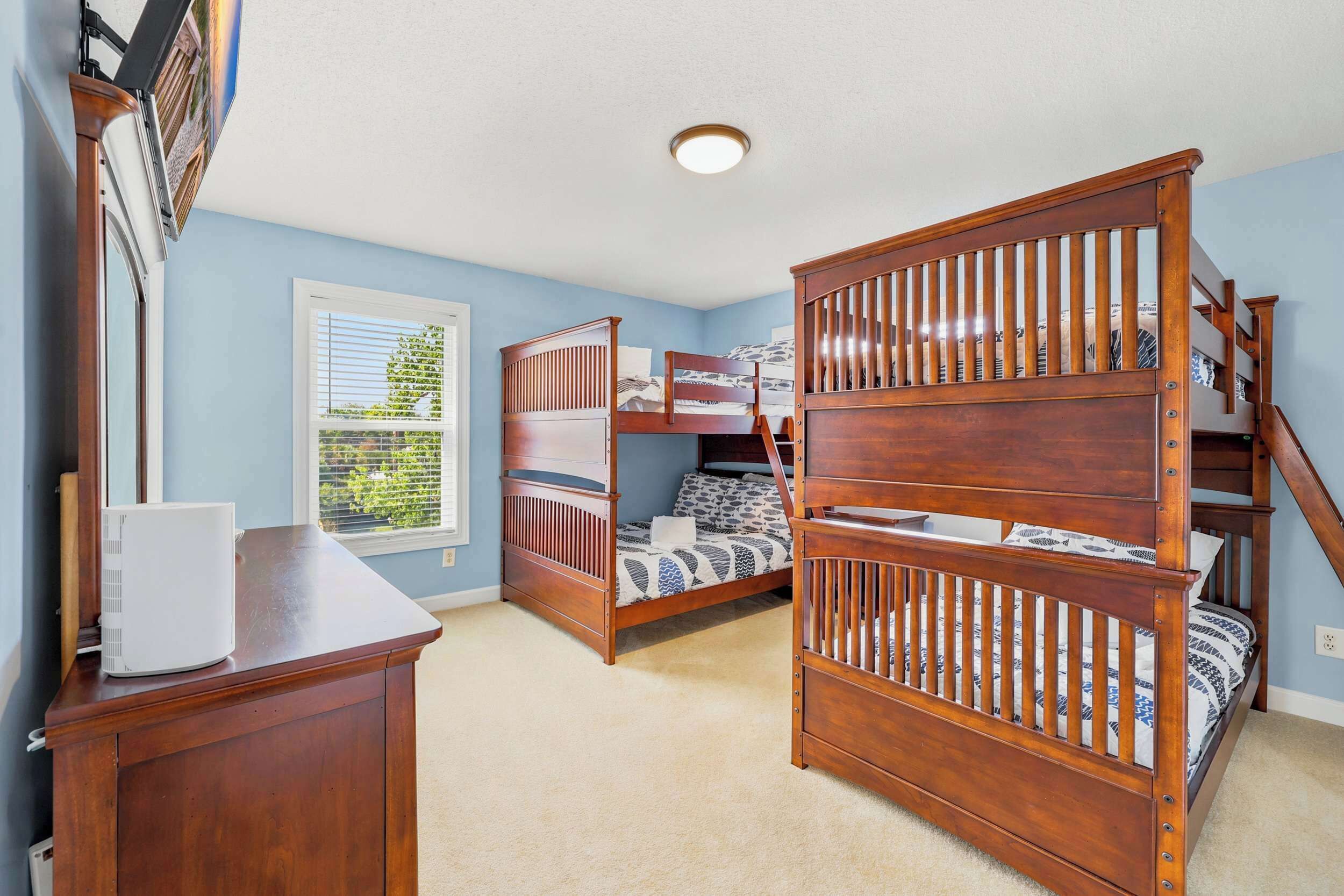 A room with a bunk bed, a desk, and a window with blinds.
