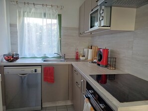 Una cocina compacta con lavavajillas, microondas y lavabo.