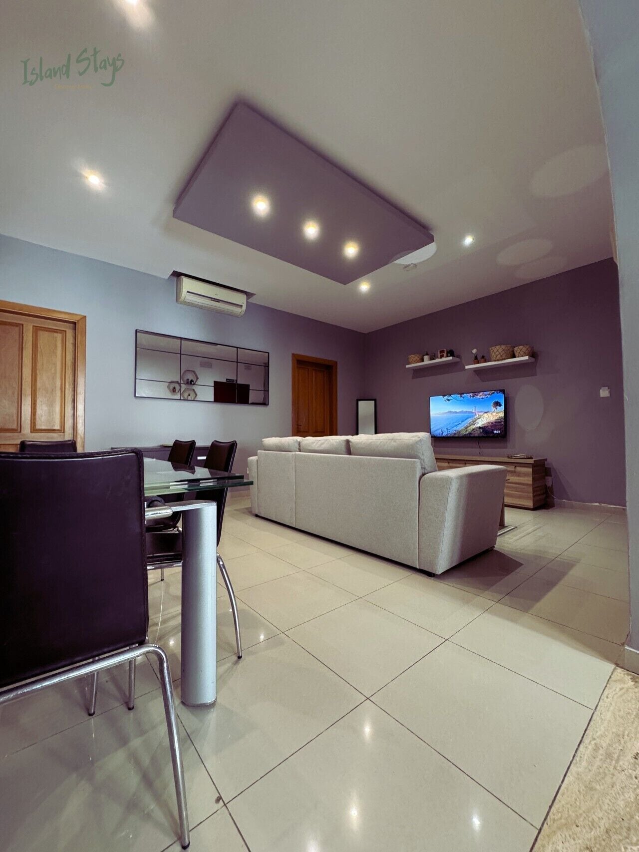 A modern living room with a sofa, TV, and dining area.