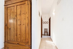 A hallway with a wooden wardrobe, a chair, and a wall-mounted light fixture. - Casa Vacanze Ervilia apartments on Lungomare E. Mattei, 50 m from the beach (Vieste)