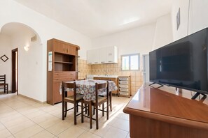A kitchen with wooden cabinets, a dining table with chairs, a TV, and a window. - Casa Vacanze Ervilia apartments on Lungomare E. Mattei, 50 m from the beach (Vieste)