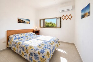 Ein Schlafzimmer mit Bett, Nachttisch, Fenster und Wanddekorationen.