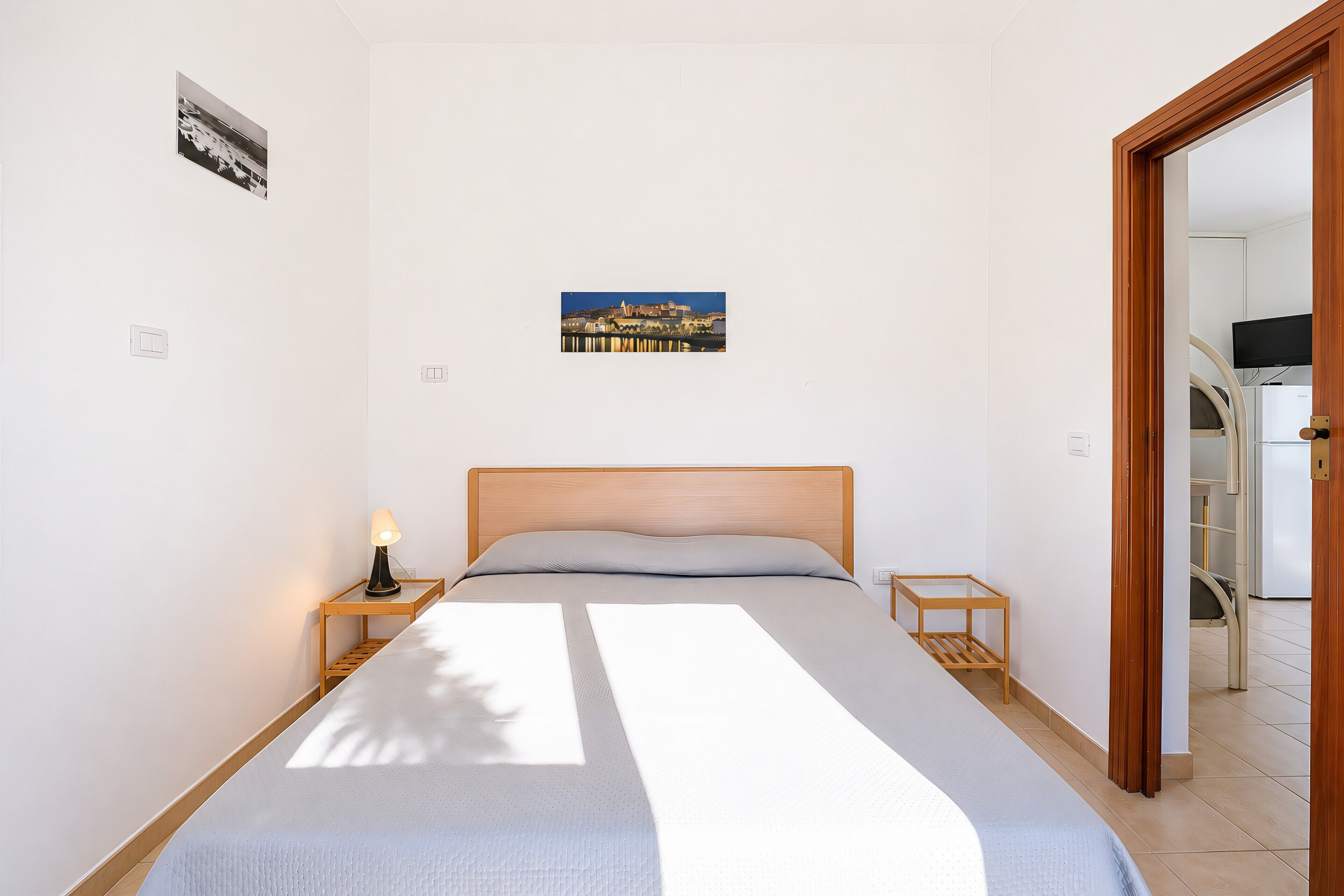 Une chambre à coucher avec un lit, une table de chevet avec une lampe, une petite table et un tableau au mur.