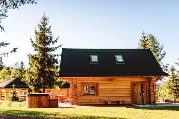Una cabaña de madera con techo oscuro, una puerta principal y un ventanal pequeño.