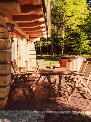 Una terraza de madera con una mesa y sillas, rodeada por un cerco de madera y árboles.