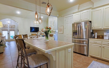 A spacious kitchen with a central island, stainless steel appliances, and a dining area with chairs and a TV.. Sweet Stay Lovely 2-bedroom condo with AC in charming Lafayette