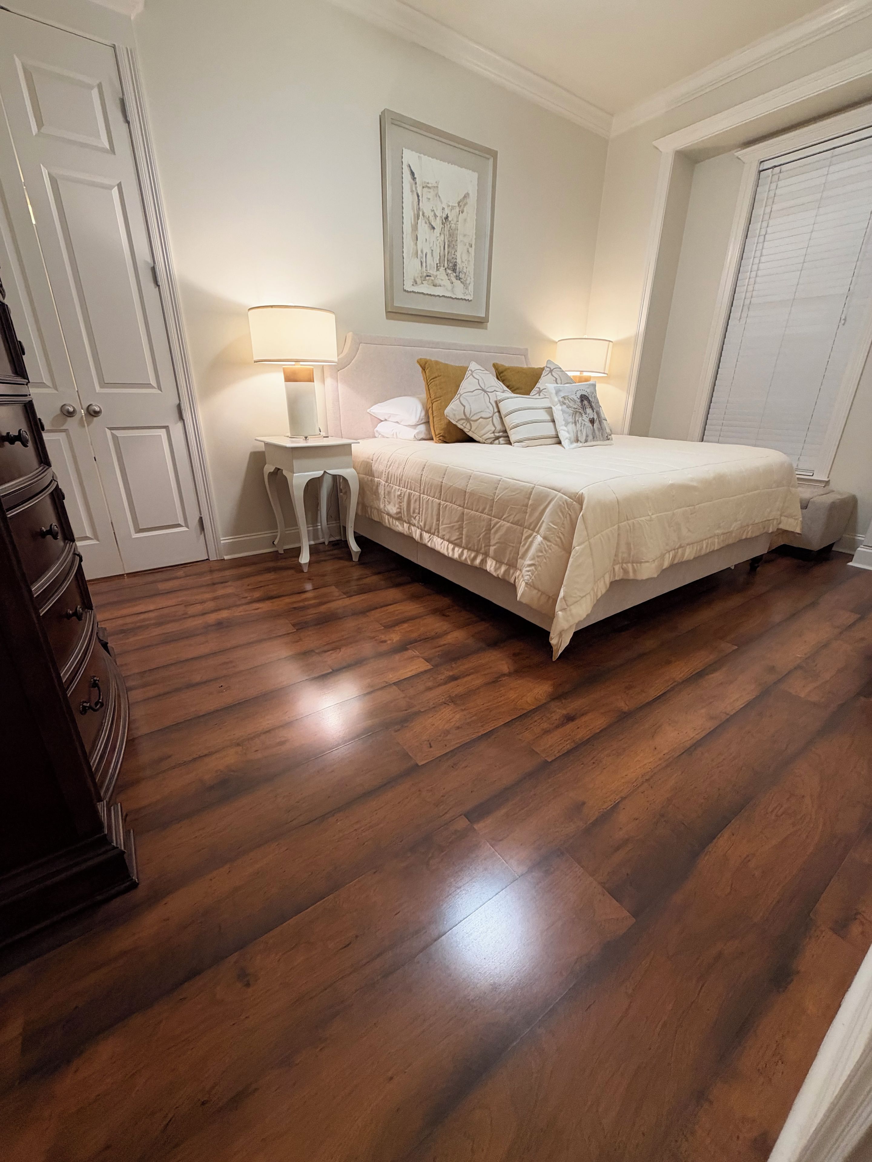 Une chambre à coucher avec un lit, des tables de chevet, une commode et une porte.