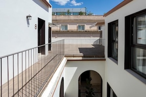 A multi-level residential building with balconies, a staircase, and a view of a neighboring building. - CSE MS MUSEO SELECT (Sevilla)
