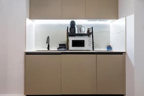 A compact kitchen with a microwave, kettle, and a small coffee maker on the countertop. - CSE MS MUSEO SELECT (Sevilla)