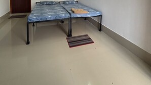 Een kamer met een bed, een plafondventilator, een deur en een lichtbalk aan de muur.