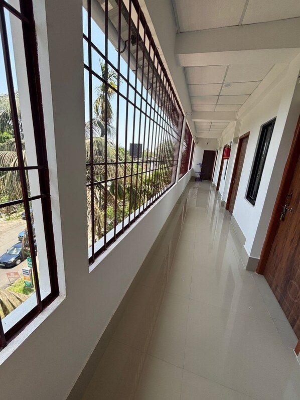 A corridor with barred windows, a tiled floor, and doors on the right.