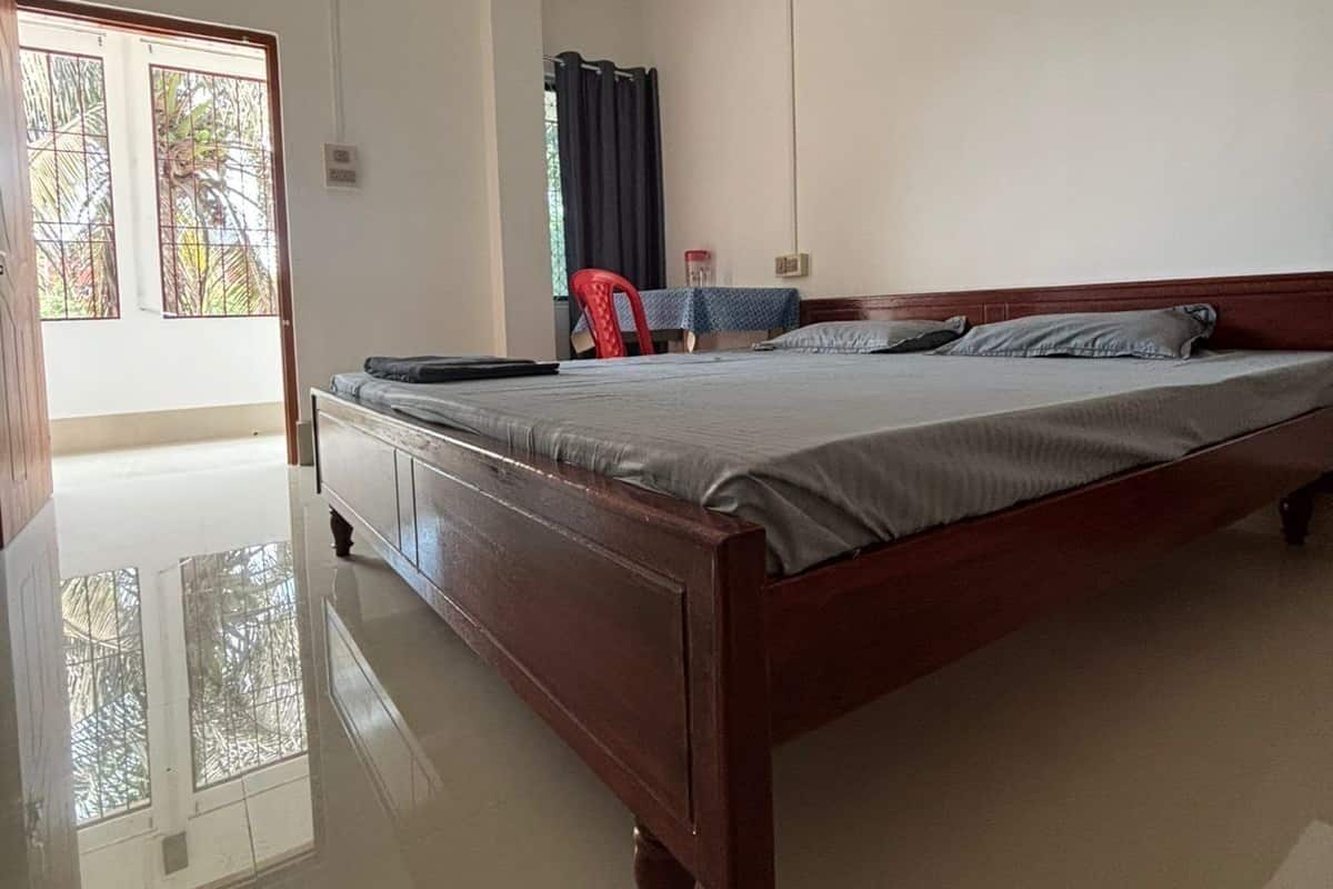 A bedroom with a wooden bed, a desk, and a chair.