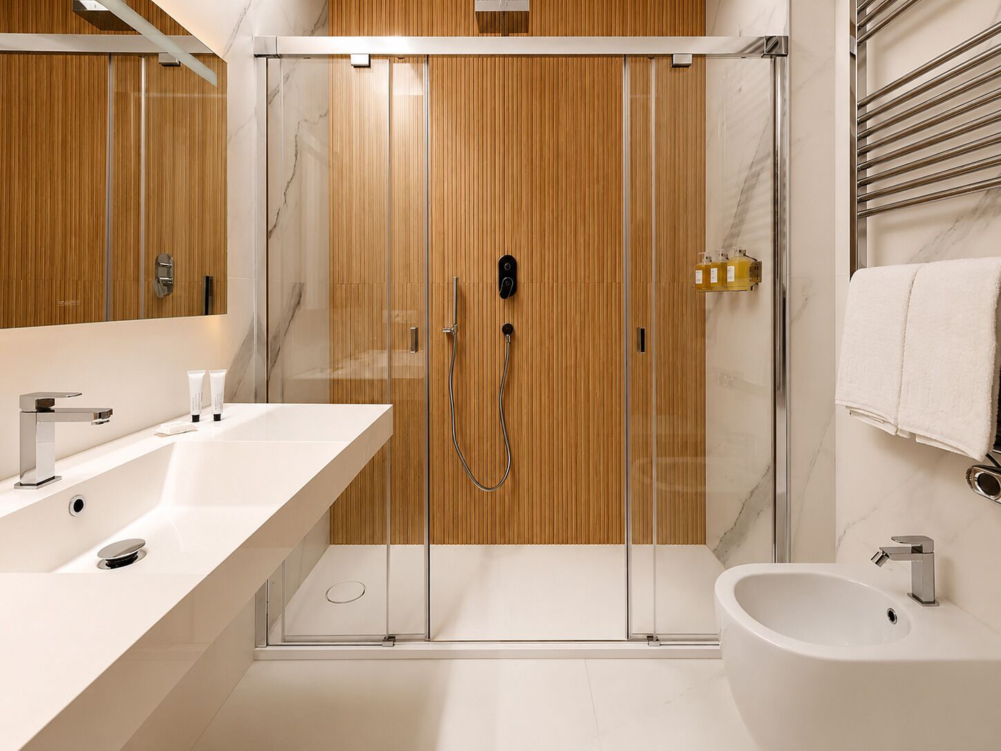 Un baño moderno con ducha envuelta en vidrio, un bidé y un espejo grande.