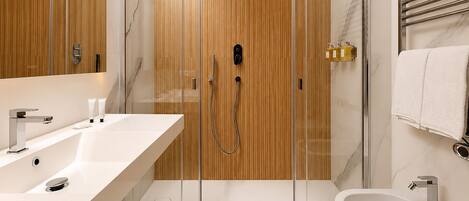 Un baño moderno con ducha envuelta en vidrio, un bidé y un espejo grande.