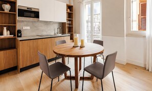 A modern kitchen with a round dining table, four chairs, and a large window. - Numa Rome Condotti (Rome)