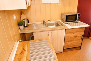 A compact kitchenette with a sink, a microwave, and a small countertop. - Cottage for 4 people, Wapnica (Wapnica)