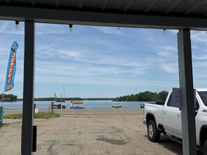 A covered area with a view of a lake, a white truck, and a flag.