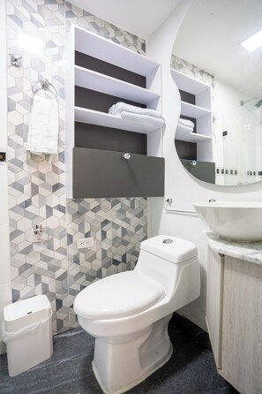 Un baño moderno con inodoro, lavamanos y toallero.