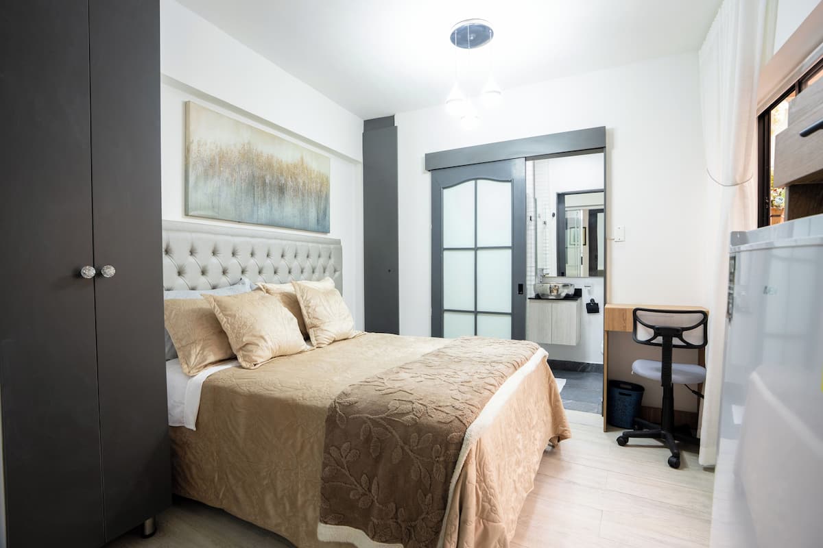 A bedroom with a bed, a wardrobe, a desk, and a chair.