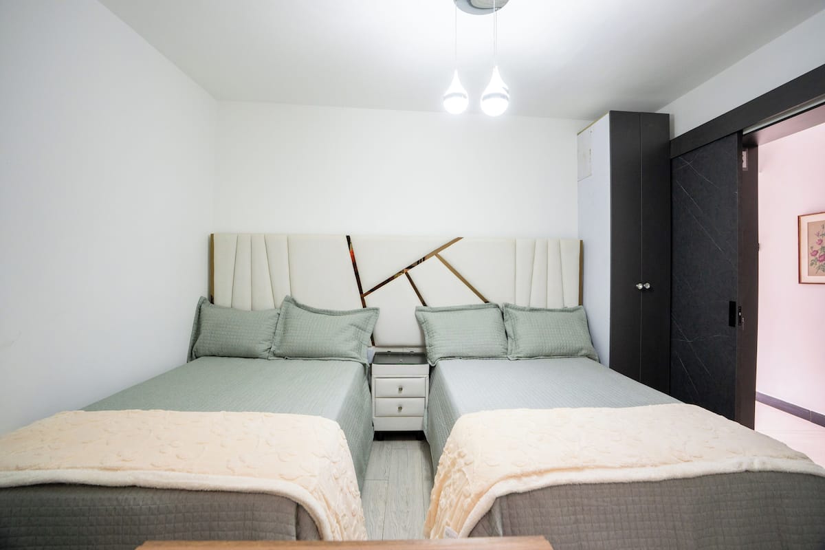 A twin bedroom with two beds, a nightstand, and a wardrobe.